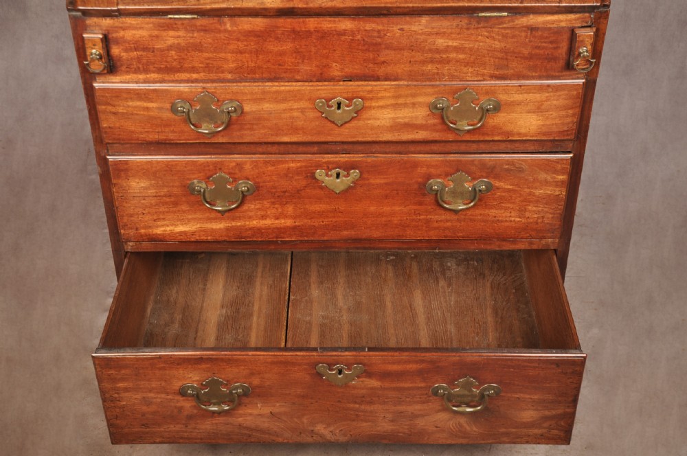 An early 18th-century mahogany slope-front bureau with three graduated drawers, brass handles, keyhole escutcheons, and bracket feet. View XII