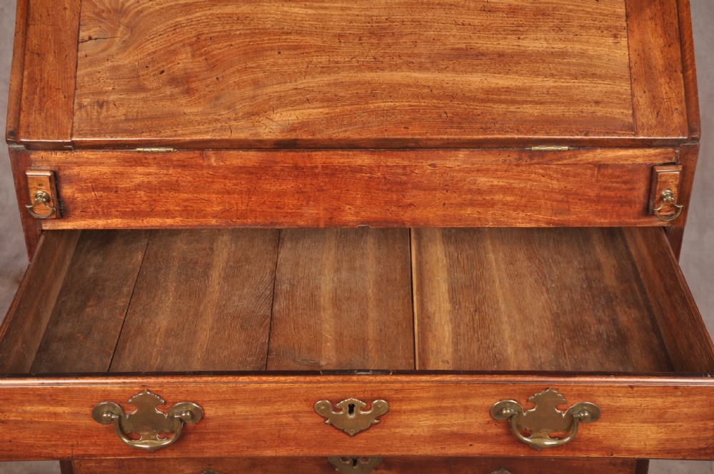 An early 18th-century mahogany slope-front bureau with three graduated drawers, brass handles, keyhole escutcheons, and bracket feet. View XIII