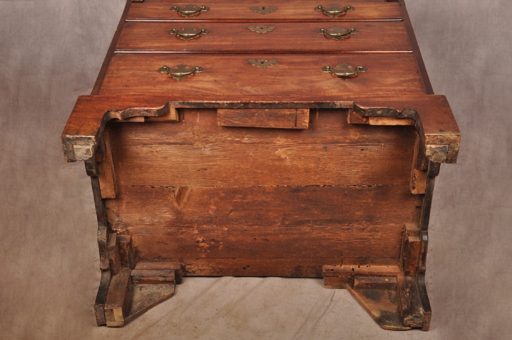 An early 18th-century mahogany slope-front bureau with three graduated drawers, brass handles, keyhole escutcheons, and bracket feet. View XIX