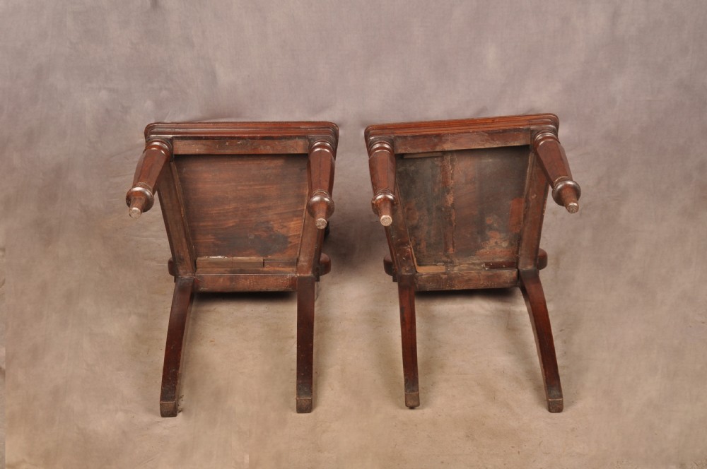A pair of mahogany Regency hall chairs featuring carved scroll tops, shield motifs, flat timber seats, and turned front legs. View IX