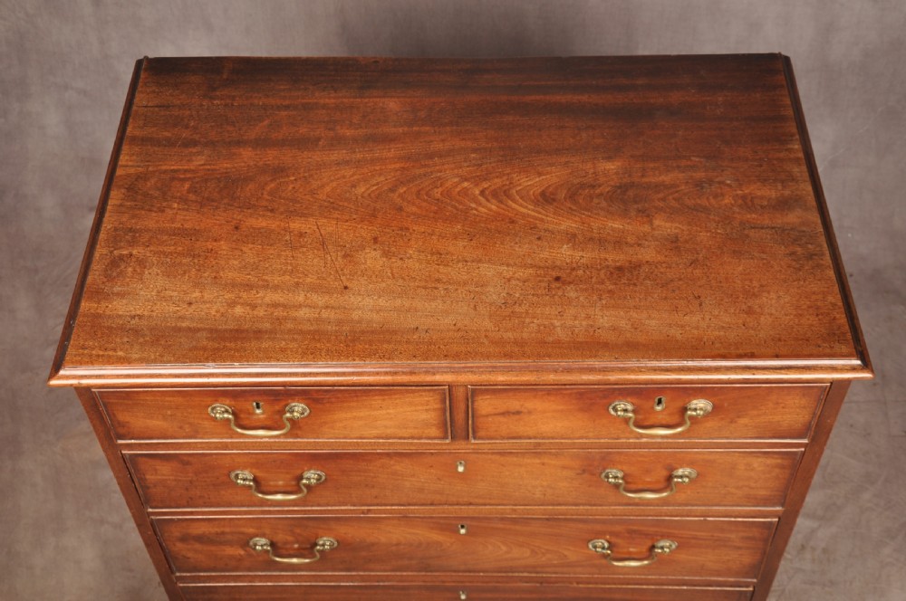 An 18th-century Georgian mahogany chest of drawers featuring two short over three long graduated drawers with brass swan-neck handles and bracket feet. View V