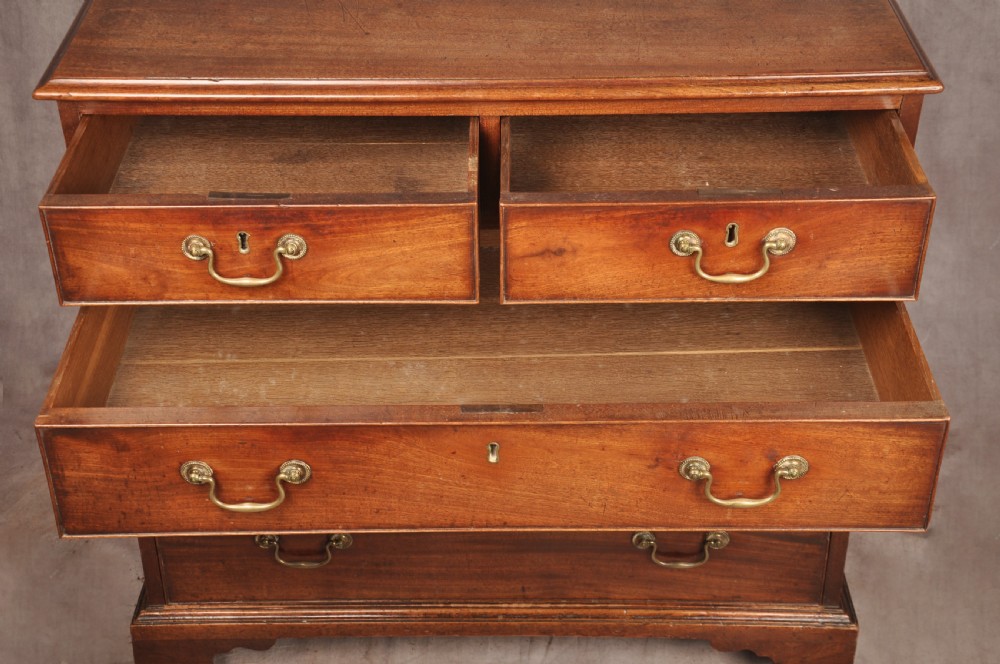 An 18th-century Georgian mahogany chest of drawers featuring two short over three long graduated drawers with brass swan-neck handles and bracket feet. View XII