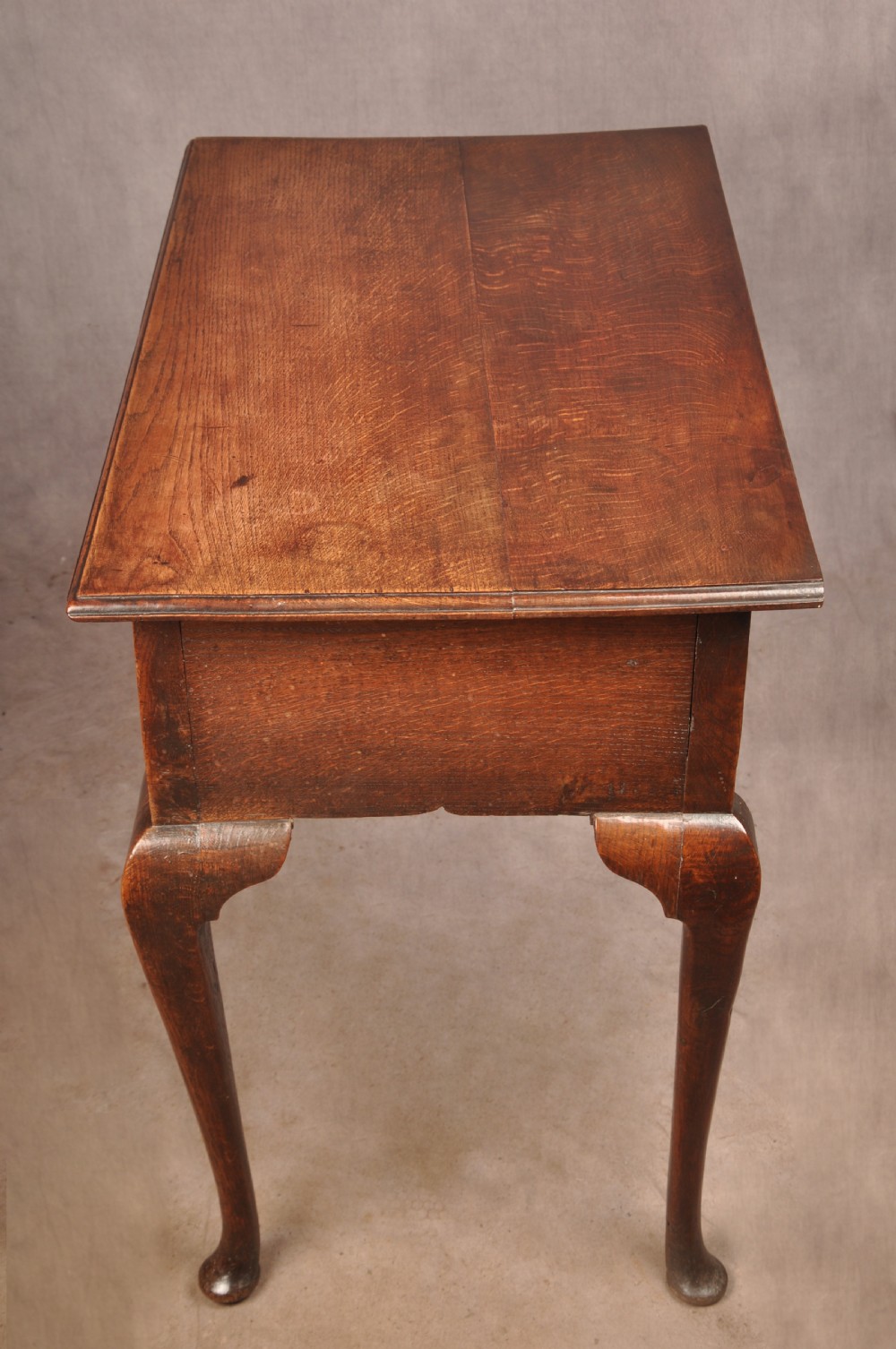 A mid-18th century George II oak lowboy side table featuring three drawers with brass handles, a shaped scroll apron, and cabriole legs ending in pad feet. View III