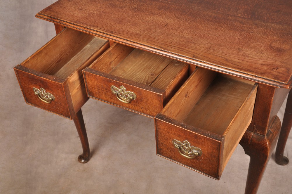 A mid-18th century George II oak lowboy side table featuring three drawers with brass handles, a shaped scroll apron, and cabriole legs ending in pad feet. View VII