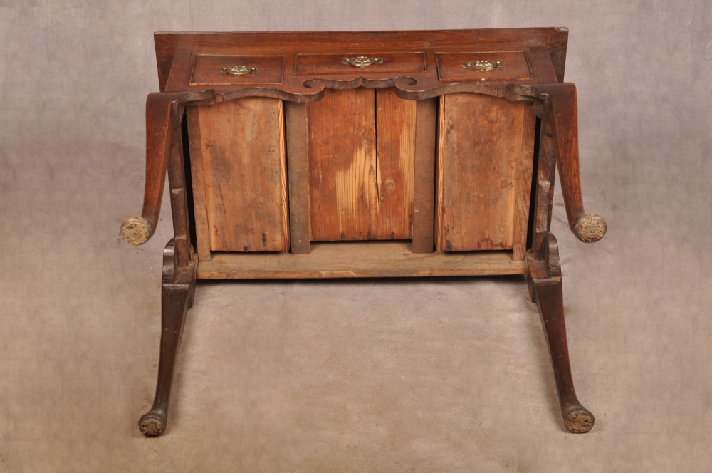 A mid-18th century George II oak lowboy side table featuring three drawers with brass handles, a shaped scroll apron, and cabriole legs ending in pad feet. View XIV