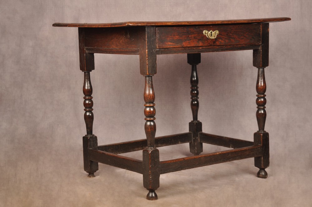 A 17th-century dark oak side table featuring a single drawer with a brass handle, turned legs, and a perimeter box stretcher. View II