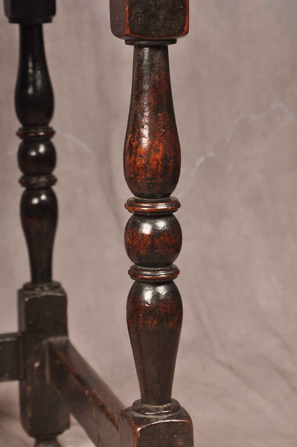 A 17th-century dark oak side table featuring a single drawer with a brass handle, turned legs, and a perimeter box stretcher. View IV