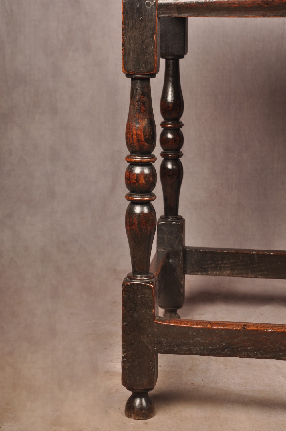 A 17th-century dark oak side table featuring a single drawer with a brass handle, turned legs, and a perimeter box stretcher. View V