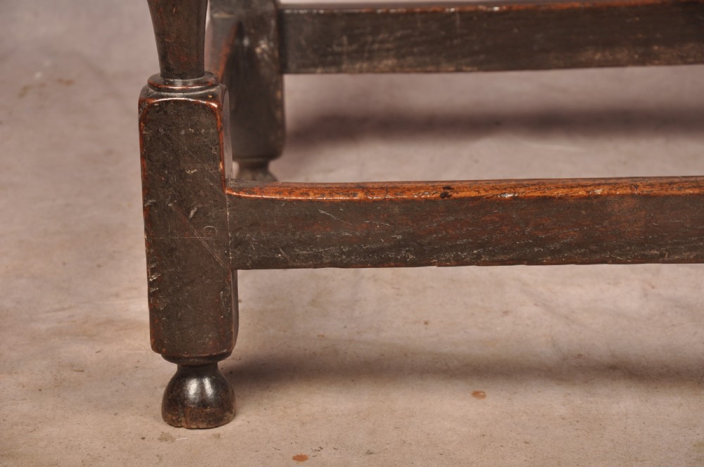 A 17th-century dark oak side table featuring a single drawer with a brass handle, turned legs, and a perimeter box stretcher. View VI