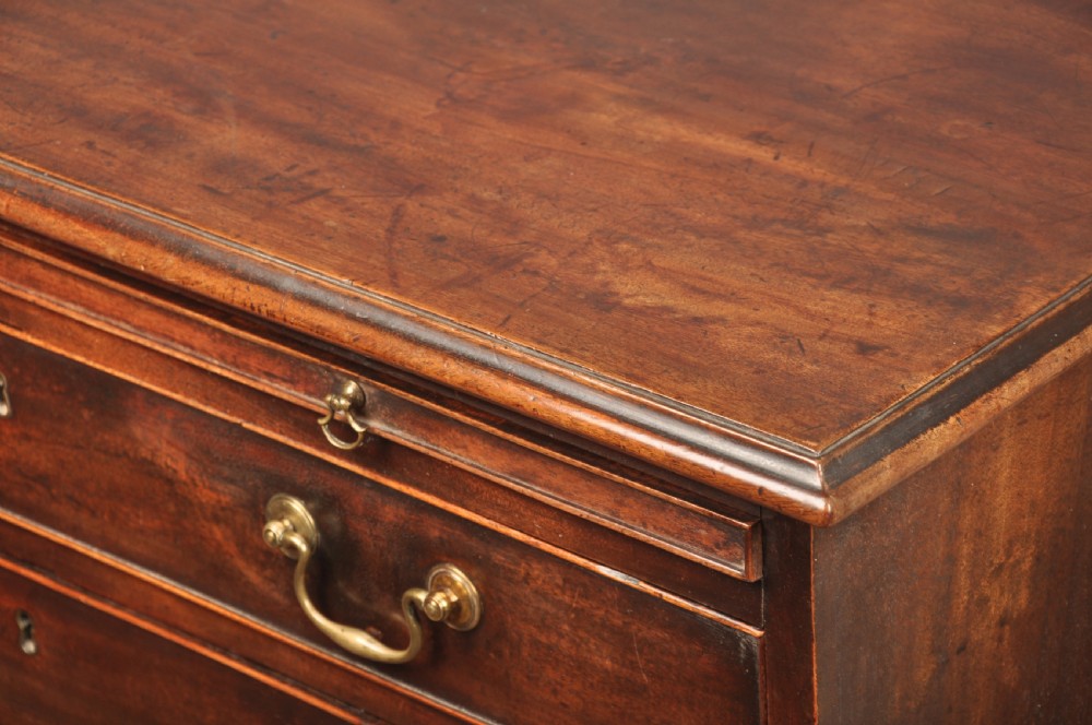 An eighteenth-century mahogany chest of drawers featuring four graduated drawers with brass swan-neck handles, a brushing slide, and bracket feet. View V