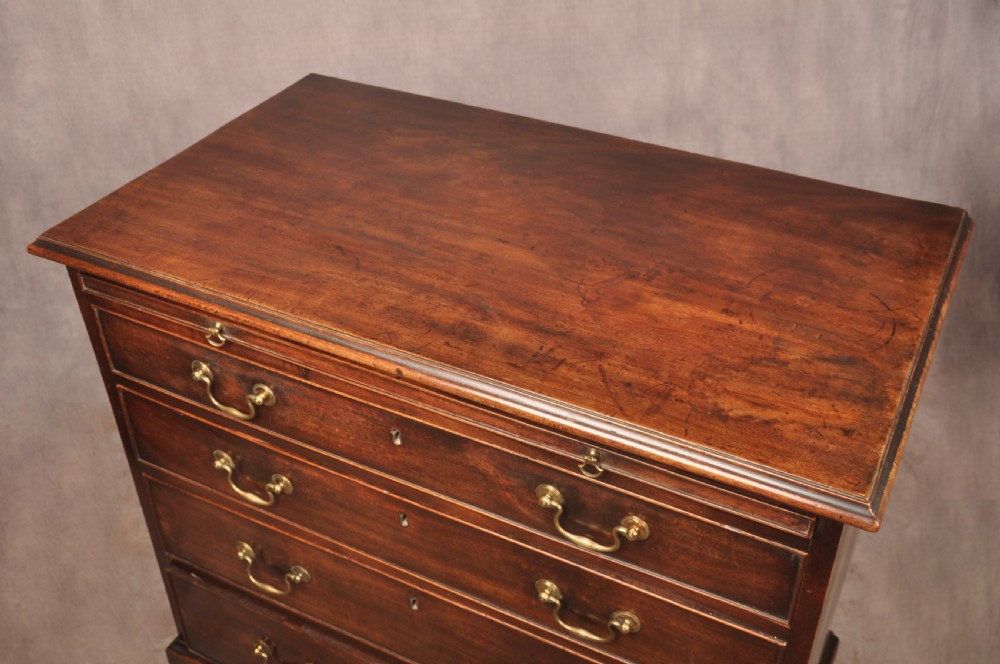 An eighteenth-century mahogany chest of drawers featuring four graduated drawers with brass swan-neck handles, a brushing slide, and bracket feet. View VII