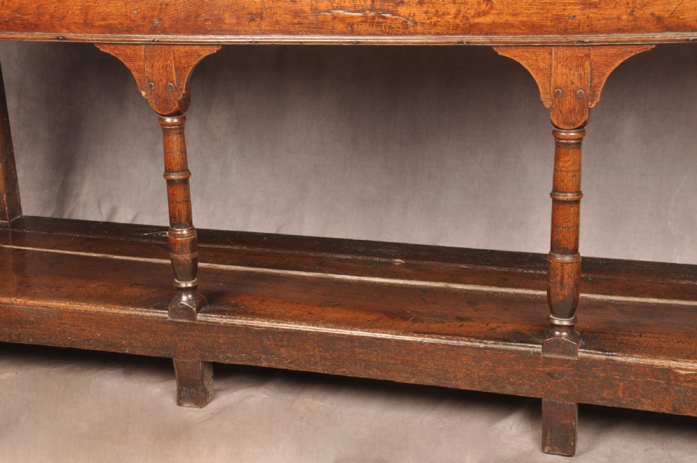 An 18th-century oak pot board dresser featuring an open tiered plate rack above three drawers with brass handles and a low shelf. View XI