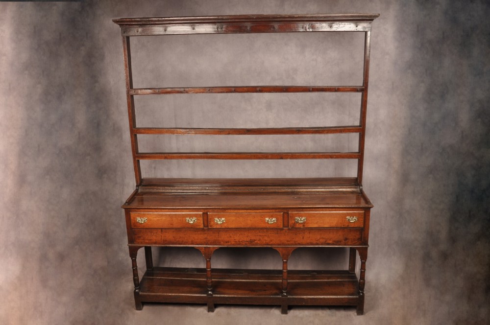 An 18th-century oak pot board dresser featuring an open tiered plate rack above three drawers with brass handles and a low shelf. View III