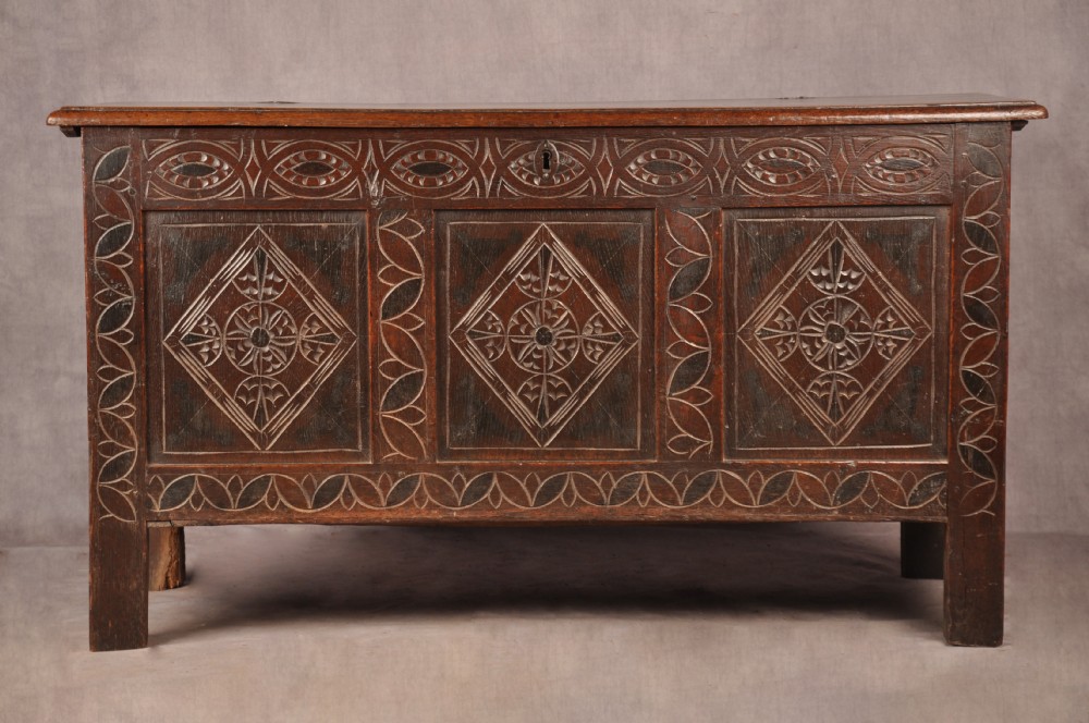 A 17th century carved oak coffer featuring three lozenge-carved front panels, leaf motifs, and ebonised detailing.