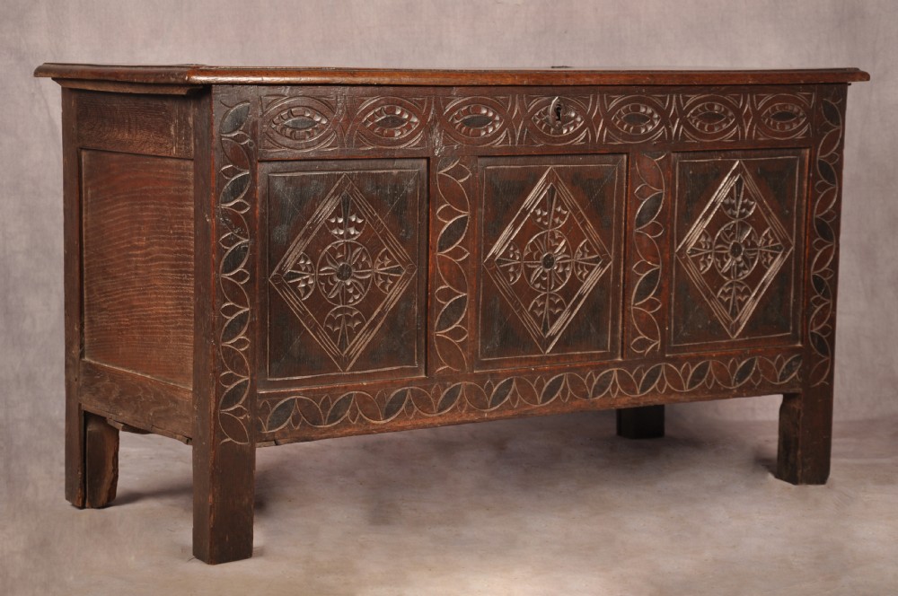 A 17th century carved oak coffer featuring three lozenge-carved front panels, leaf motifs, and ebonised detailing. View II