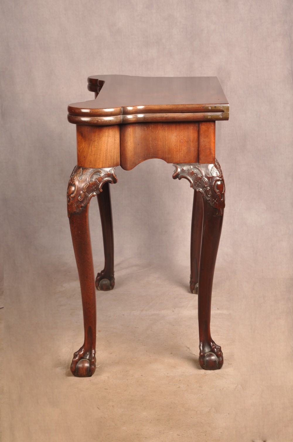 An 18th-century George II mahogany card table with a fold-over shaped top, a frieze drawer, and carved cabriole legs with claw-and-ball feet. View II