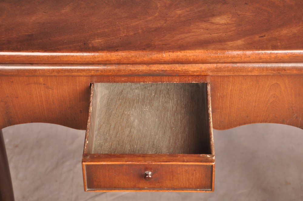 An 18th-century George II mahogany card table with a fold-over shaped top, a frieze drawer, and carved cabriole legs with claw-and-ball feet. View X