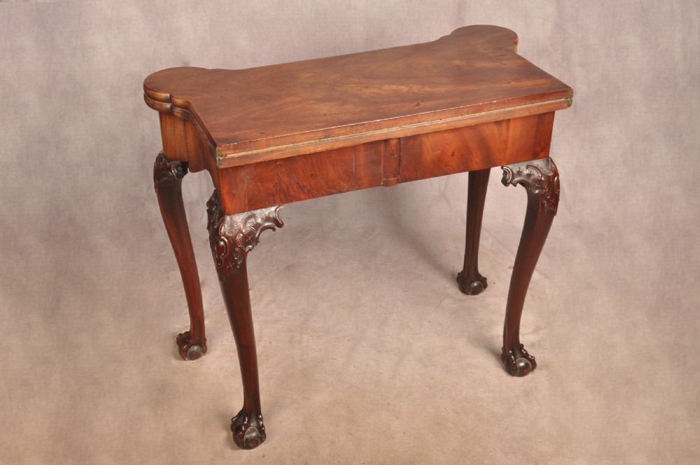 An 18th-century George II mahogany card table with a fold-over shaped top, a frieze drawer, and carved cabriole legs with claw-and-ball feet. View XVI