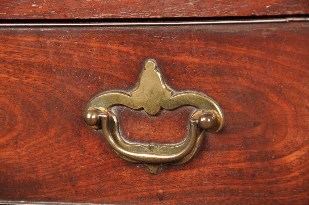 An early eighteenth-century mahogany chest of drawers featuring four graduated drawers, brass handles, a brushing slide, and bracket feet. View II
