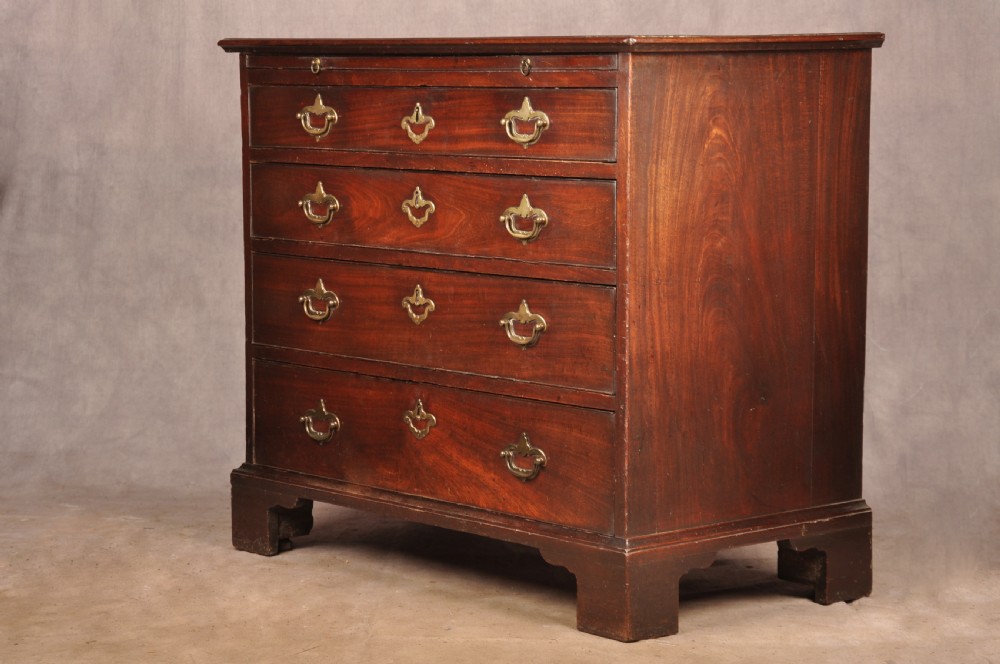 An early eighteenth-century mahogany chest of drawers featuring four graduated drawers, brass handles, a brushing slide, and bracket feet. View V