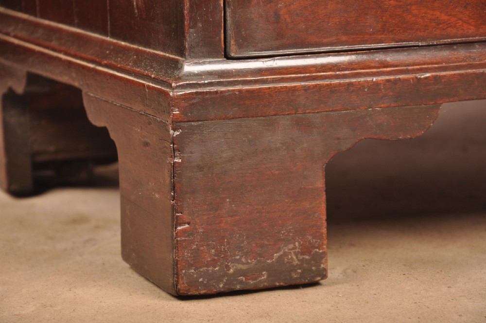 An early eighteenth-century mahogany chest of drawers featuring four graduated drawers, brass handles, a brushing slide, and bracket feet. View XVI
