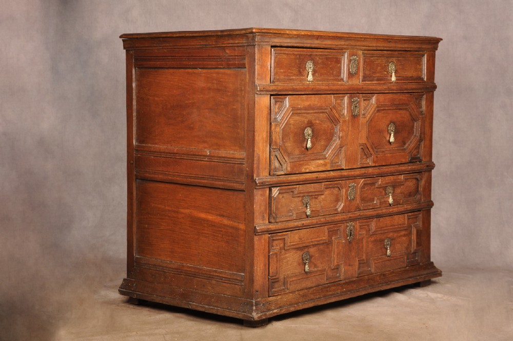 A 17th-century Charles II solid oak chest of drawers featuring geometric applied mouldings and brass teardrop handles. View II