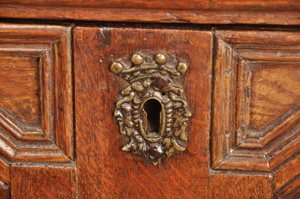 A 17th-century Charles II solid oak chest of drawers featuring geometric applied mouldings and brass teardrop handles. View V