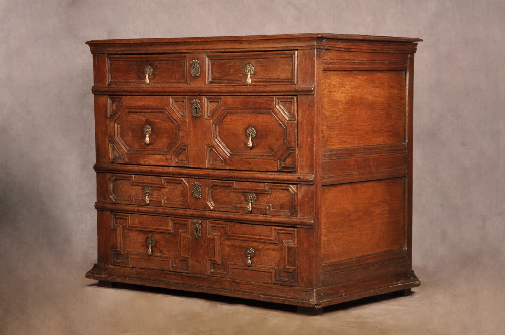 A 17th-century Charles II solid oak chest of drawers featuring geometric applied mouldings and brass teardrop handles. View VI