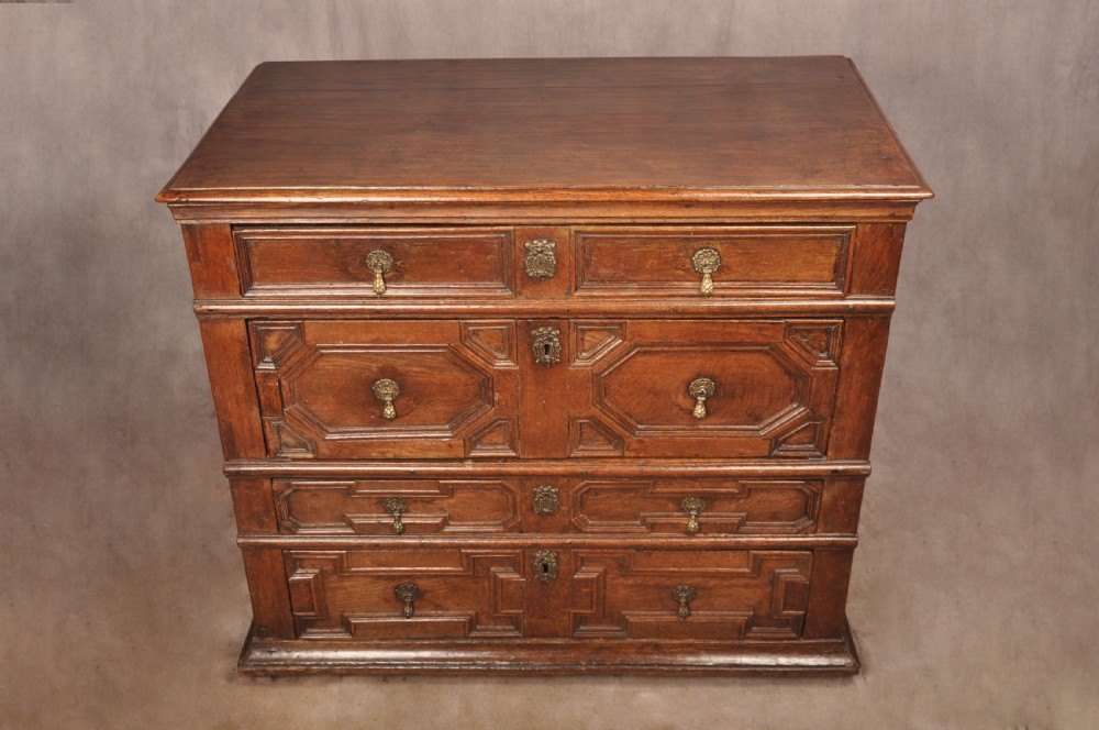 A 17th-century Charles II solid oak chest of drawers featuring geometric applied mouldings and brass teardrop handles. View VII