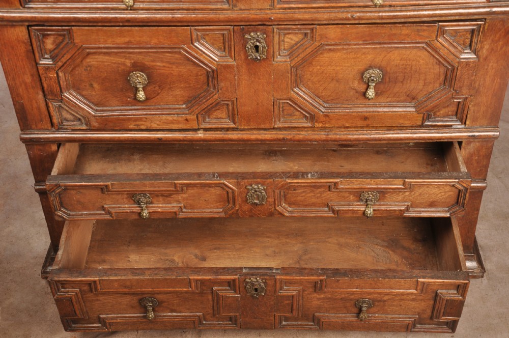A 17th-century Charles II solid oak chest of drawers featuring geometric applied mouldings and brass teardrop handles. View XI