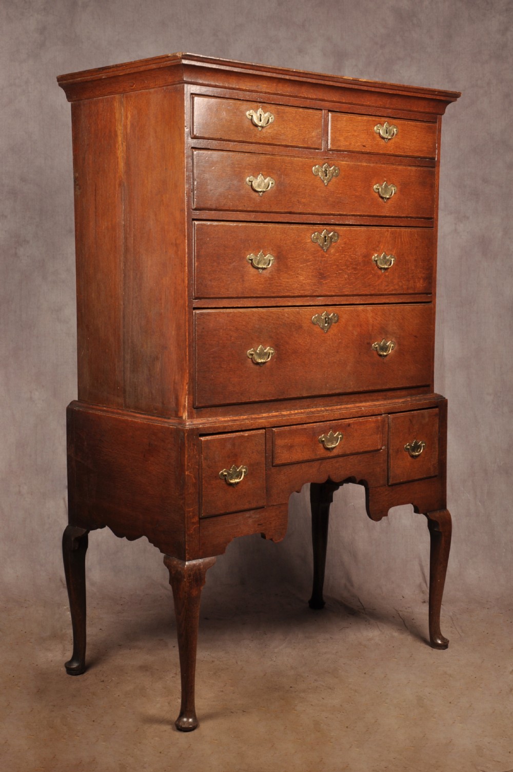 An 18th-century George I oak chest on stand featuring multiple graduated drawers with brass handles, resting on shaped cabriole legs. View V