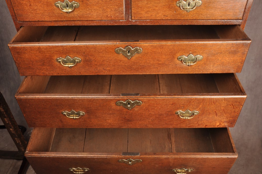 An 18th-century George I oak chest on stand featuring multiple graduated drawers with brass handles, resting on shaped cabriole legs. View VIII