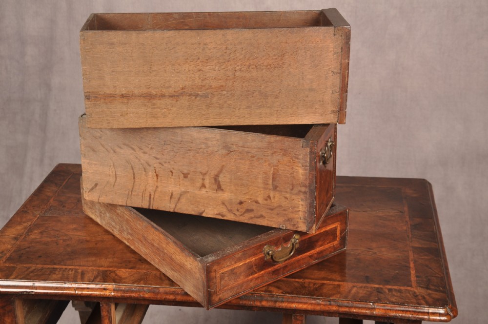 An early 18th century walnut lowboy featuring three drawers with brass handles, a shaped apron, and shell-carved cabriole legs. View X