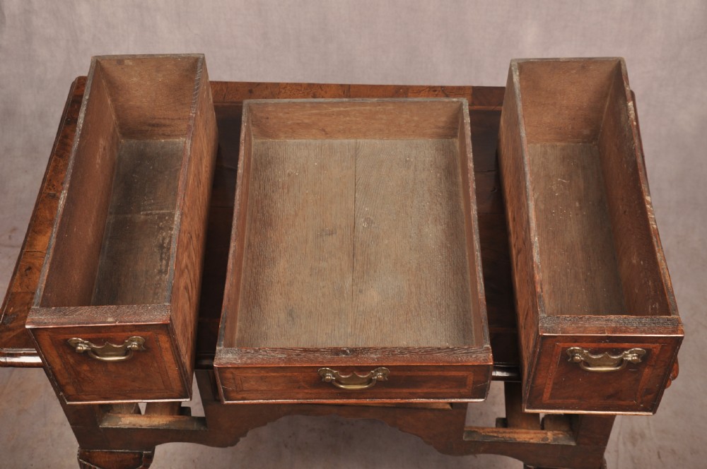 An early 18th century walnut lowboy featuring three drawers with brass handles, a shaped apron, and shell-carved cabriole legs. View XI