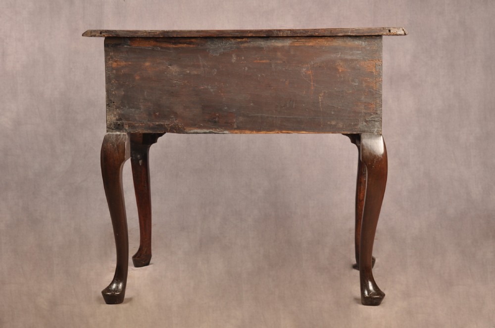 An early 18th century walnut lowboy featuring three drawers with brass handles, a shaped apron, and shell-carved cabriole legs. View XVII