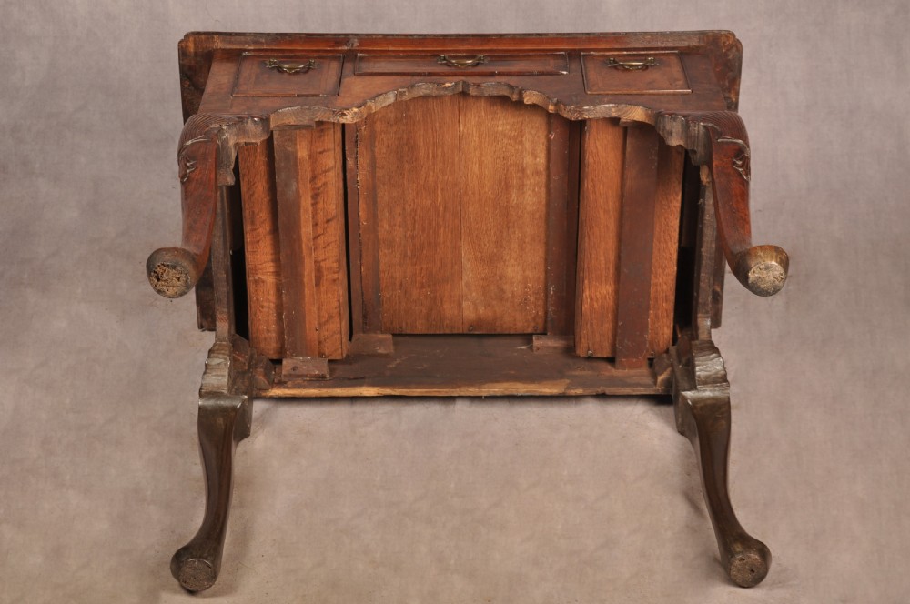 An early 18th century walnut lowboy featuring three drawers with brass handles, a shaped apron, and shell-carved cabriole legs. View XVIII