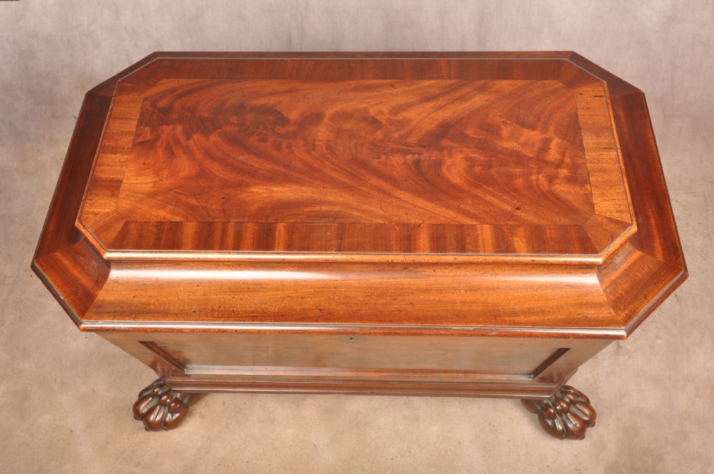A Regency flame mahogany sarcophagus-shaped wine cooler featuring a hinged stepped lid, reeded corners, and carved paw feet. View IV