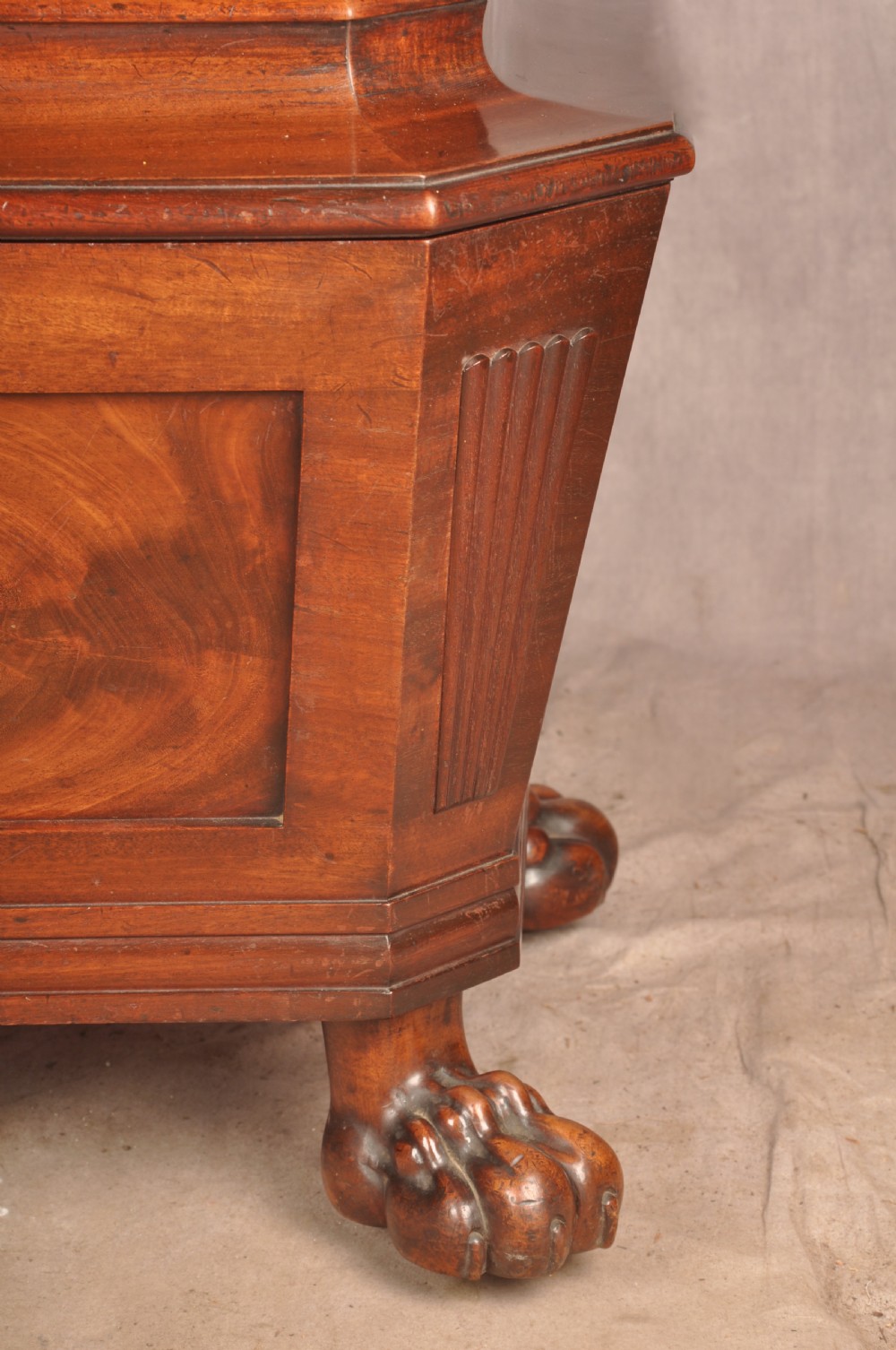 A Regency flame mahogany sarcophagus-shaped wine cooler featuring a hinged stepped lid, reeded corners, and carved paw feet. View VIII