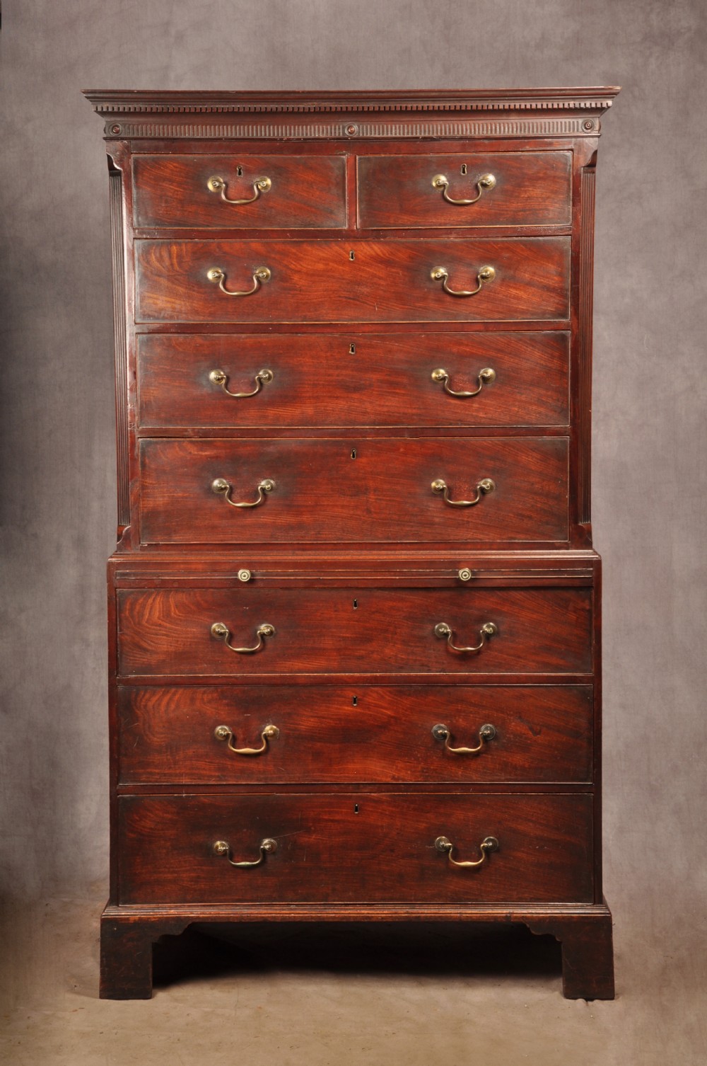 An 18th-century mahogany tallboy featuring stacked upper and lower drawer sections, brass swan-neck handles, fluted sides, and bracket feet.