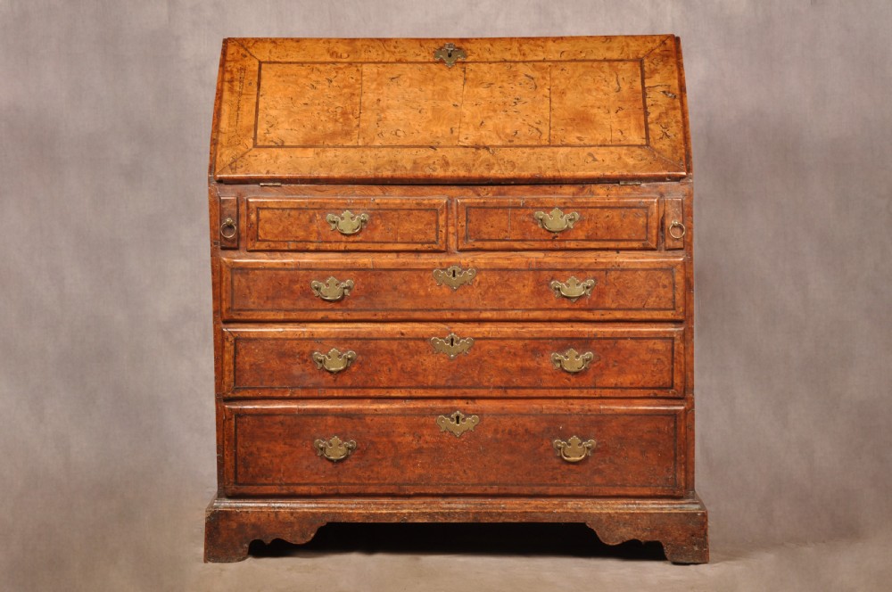 An early 18th-century burr elm slant-front writing bureau featuring figured wood grain, brass drop handles, and bracket feet. View II