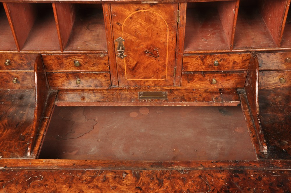 An early 18th-century burr elm slant-front writing bureau featuring figured wood grain, brass drop handles, and bracket feet. View VII