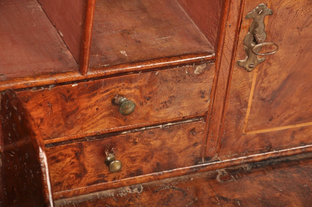 An early 18th-century burr elm slant-front writing bureau featuring figured wood grain, brass drop handles, and bracket feet. View VIII