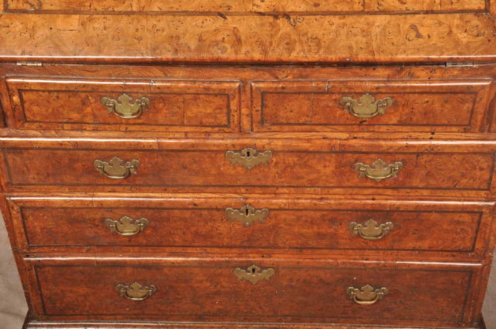 An early 18th-century burr elm slant-front writing bureau featuring figured wood grain, brass drop handles, and bracket feet. View XIII