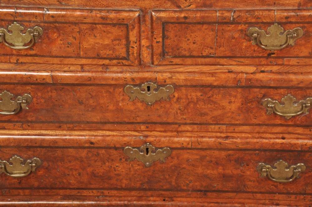 An early 18th-century burr elm slant-front writing bureau featuring figured wood grain, brass drop handles, and bracket feet. View XIV
