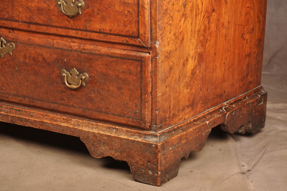 An early 18th-century burr elm slant-front writing bureau featuring figured wood grain, brass drop handles, and bracket feet. View XV
