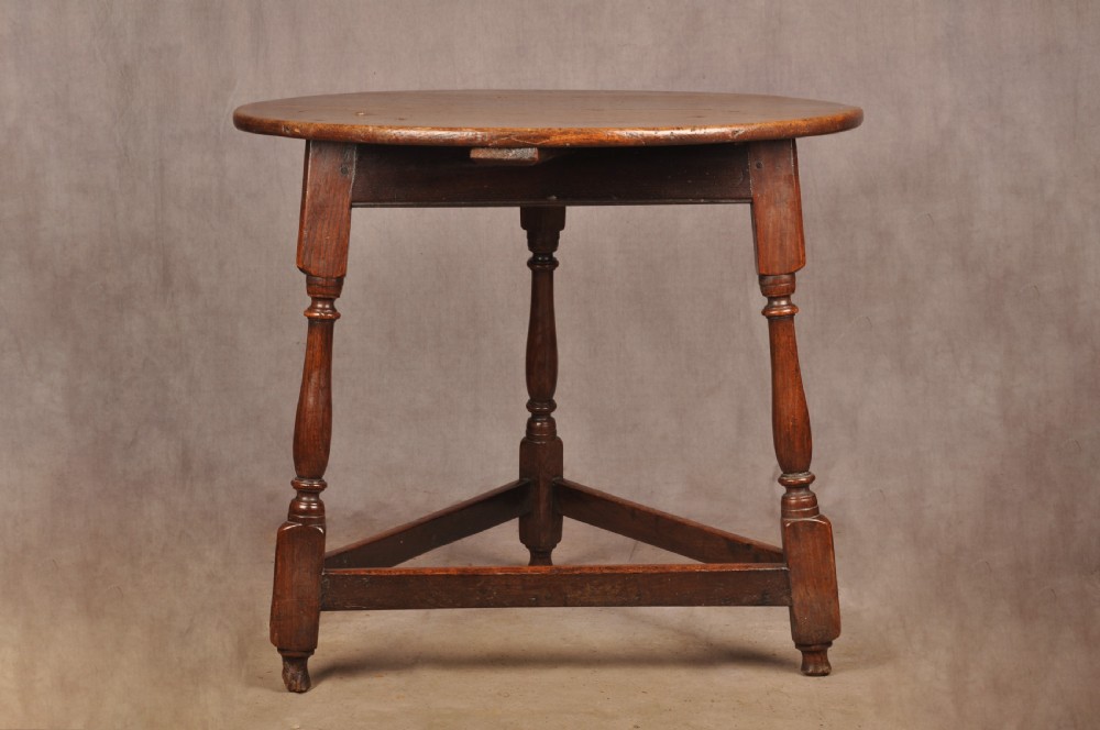 An 18th-century circular timber cricket table with three turned legs connected by a low triangular stretcher. View II