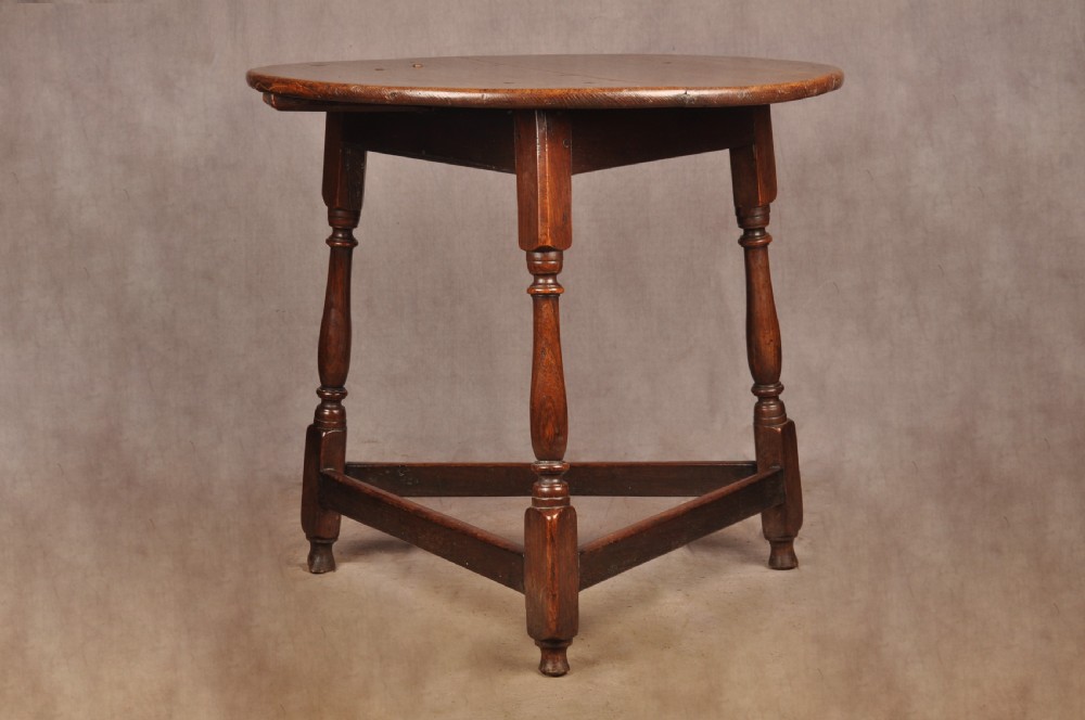 An 18th-century circular timber cricket table with three turned legs connected by a low triangular stretcher. View III