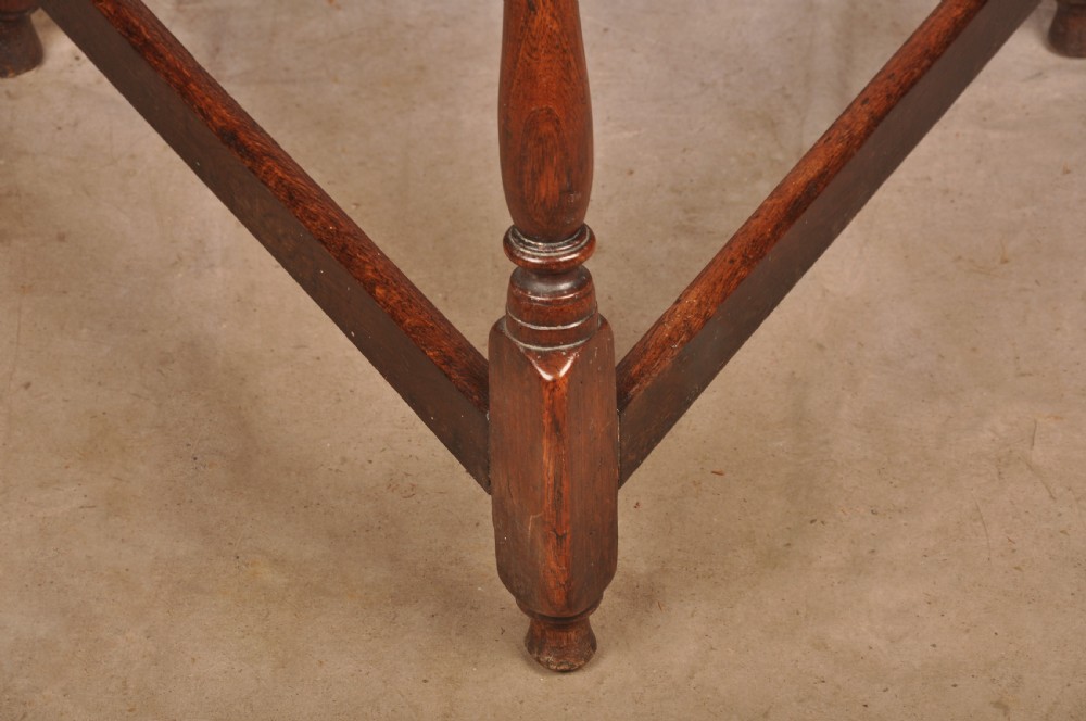 An 18th-century circular timber cricket table with three turned legs connected by a low triangular stretcher. View V