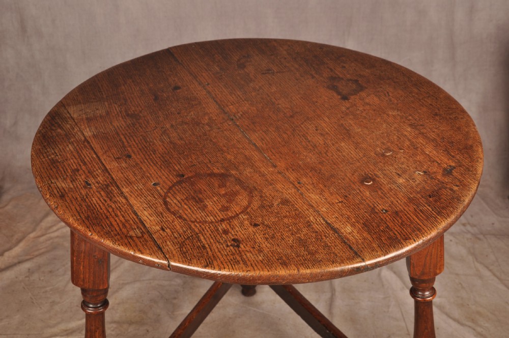 An 18th-century circular timber cricket table with three turned legs connected by a low triangular stretcher. View VI