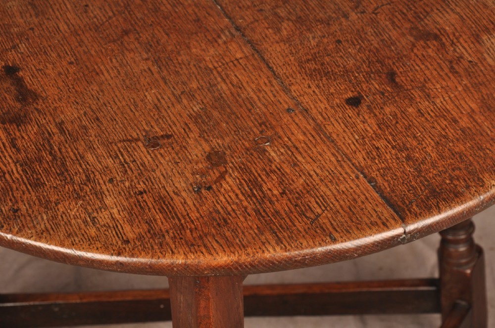 An 18th-century circular timber cricket table with three turned legs connected by a low triangular stretcher. View VII